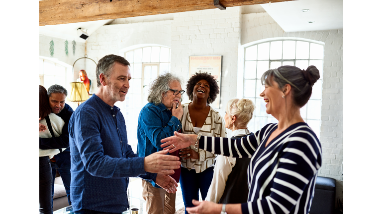 Mature friends greeting each other at social gathering