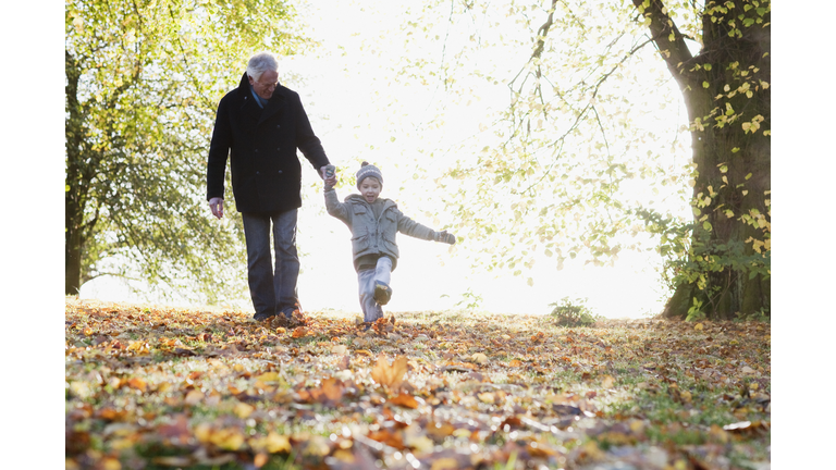Grandfather walking outdoors with grandson in autumn