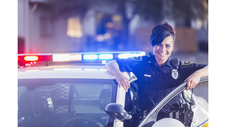 Female police officer standing next to patrol car