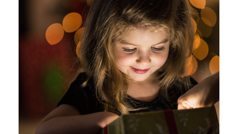 Curious girl peeks inside a Christmas present