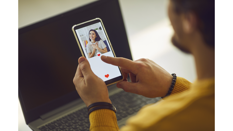 Single man looking at pretty young woman's photo on dating app and pressing like button