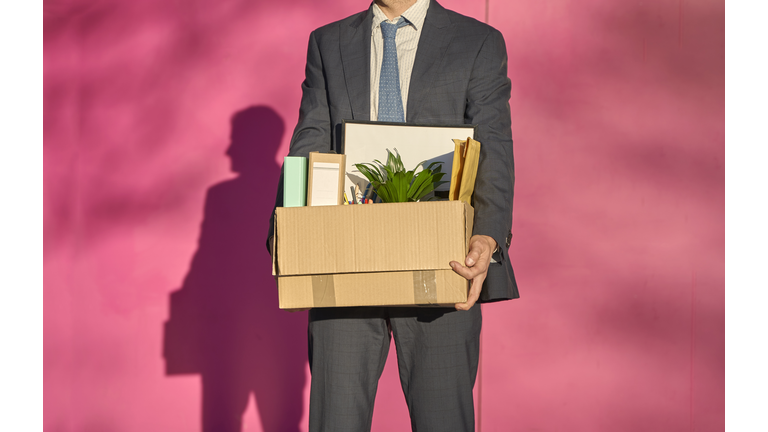 Businessman carrying box with personal belongings on sunny day