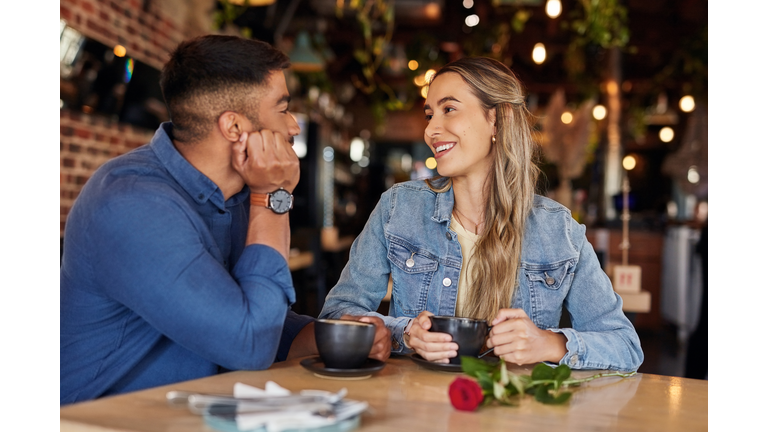 Coffee shop, date and couple of friends with rose for valentines day, anniversary or love in restaurant bokeh. Happy diversity people or woman with love partner at cafe at night for social talking