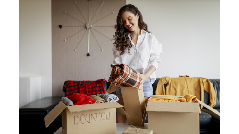 Woman sorting clothing and packing donation box