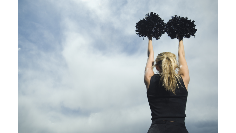 Rear view of cheerleader with pom poms