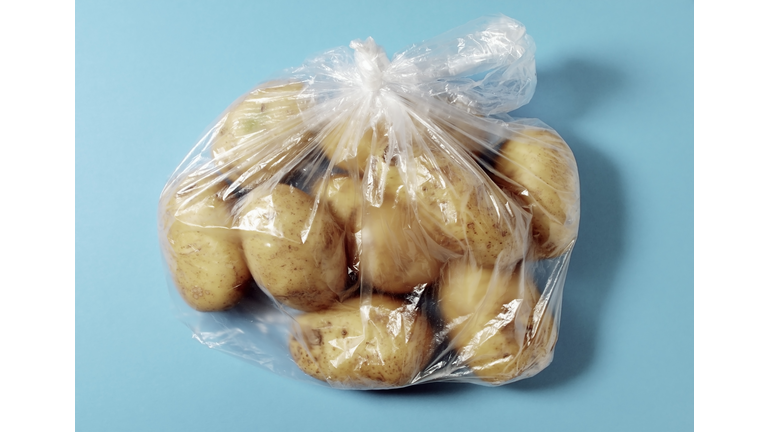 Bunch of potatoes packed in plastic bag over colored background