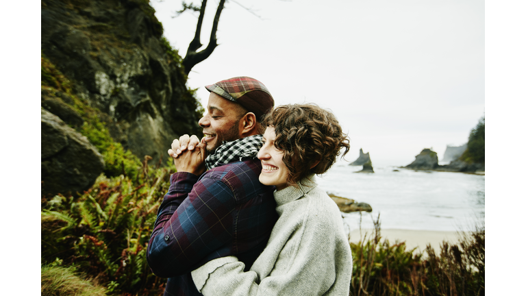 Laughing couple embracing at beach overlook