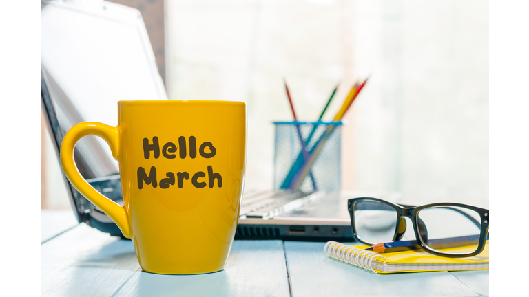 Hello march - inscription on yellow morning cup of coffee or tea at business office background. Spring time concept