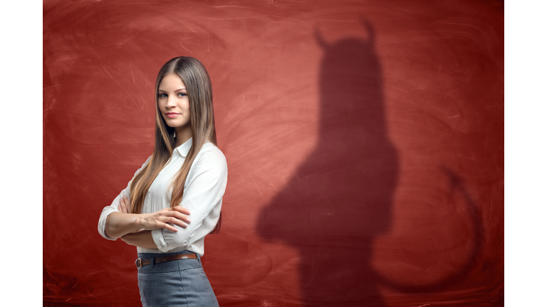 Young businesswoman is casting shadow of devil on rusty orange