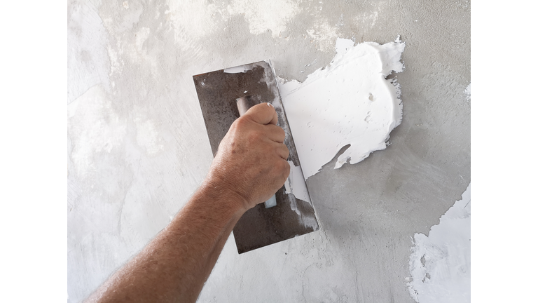 Builder using plastering tool for finishing old wall.