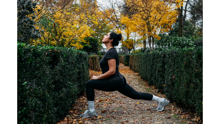 Woman stretching in park in a beautiful autumn day