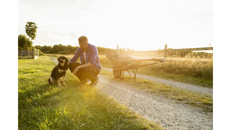 Man with dog in grassy field at farm against sky