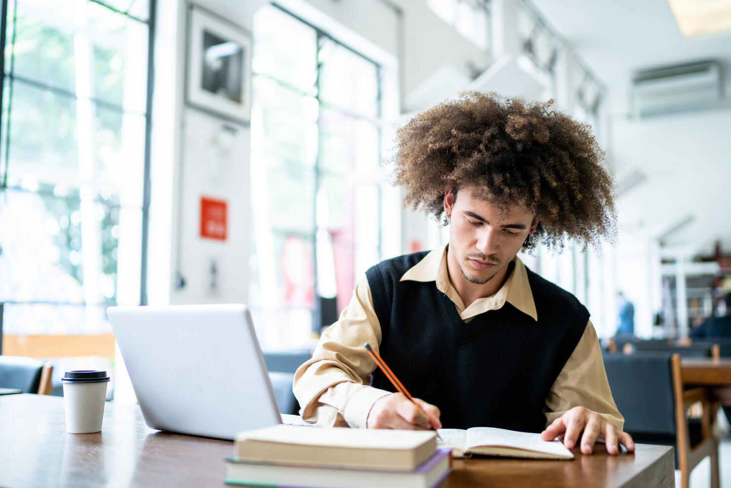 Young man studying using a laptop in a library