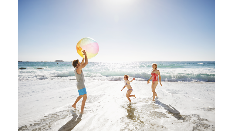 Family playing with ball by the ocean