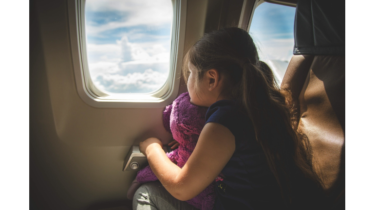 Girl sitting in airplane looking out of window