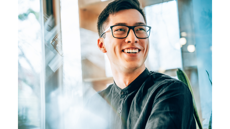 Portrait of a young handsome Asian entrepreneur, smiling and looking forward to the future innovations