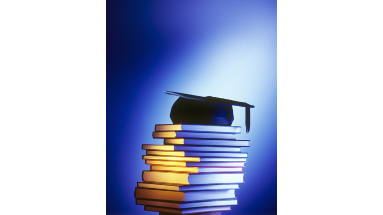 Mortarboard on pile of books representing University Education