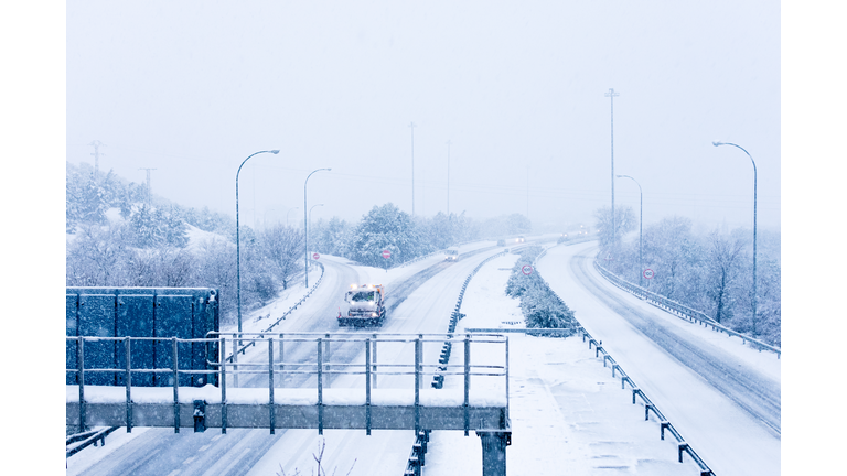 View of a snow-covered Spanish highway and a snowplow removing snow.