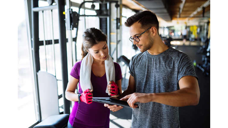 Woman and personal trainer making exercise plan in gym