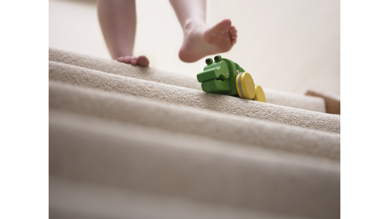 Woman about to slip on toy left on staircase