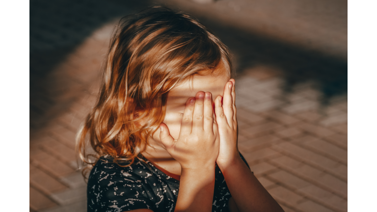 Preschool child covers his face with his hands