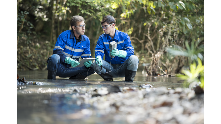 Environmentalists take water samples and measure dissolved oxygen from a forest river by micrometer instrument. Water research and development.