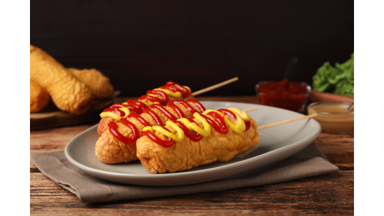 Delicious corn dogs with mustard and ketchup on wooden table