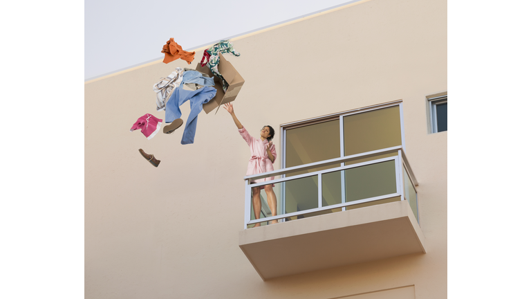 Mixed race woman throwing clothes off balcony