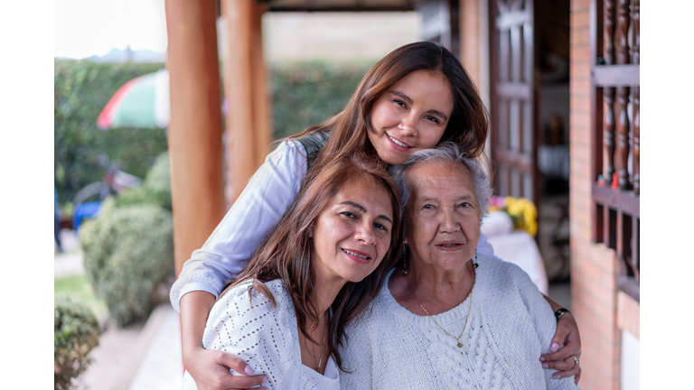 Portrait of grandmother, daughter and granddaughter facing camera smiling very cheerfully