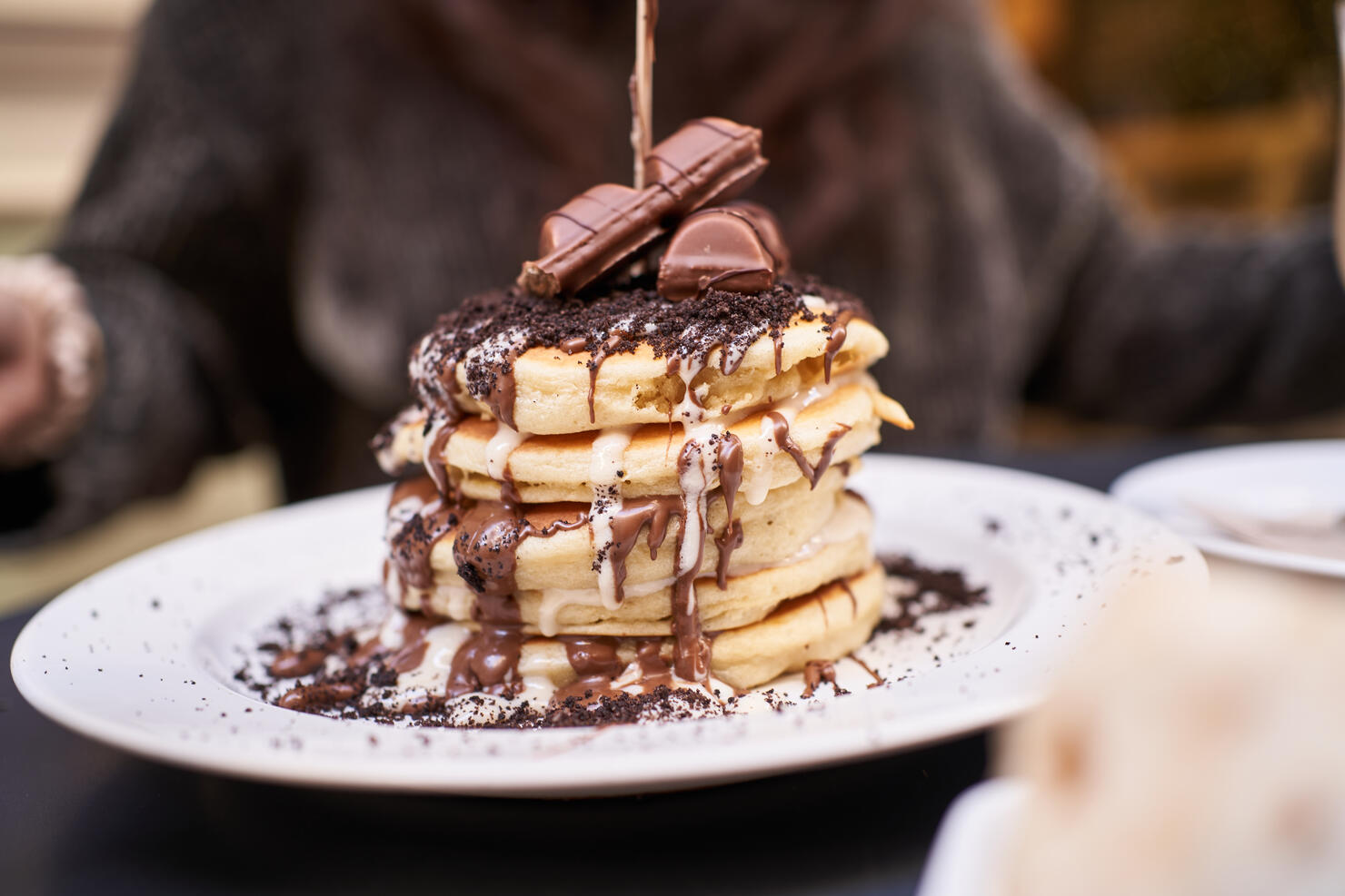 Crop person served delicious pancakes with chocolate topping in cafe