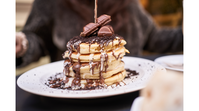 Crop person served delicious pancakes with chocolate topping in cafe