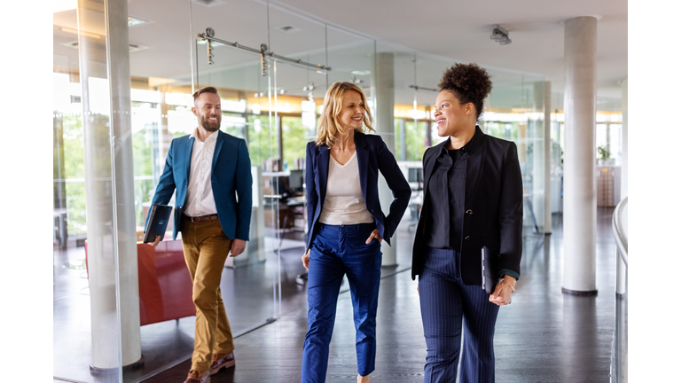 Team of corporate professionals moving through the office corridor