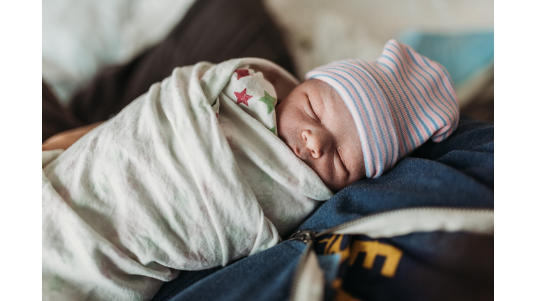 Close up of swaddled newborn in hat minutes after birth in hospital