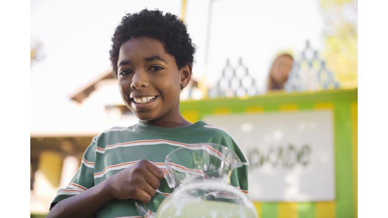 Smiling boy holding lemonade pitcher