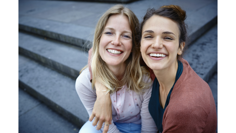 Portrait of two happy women embracing on stairs