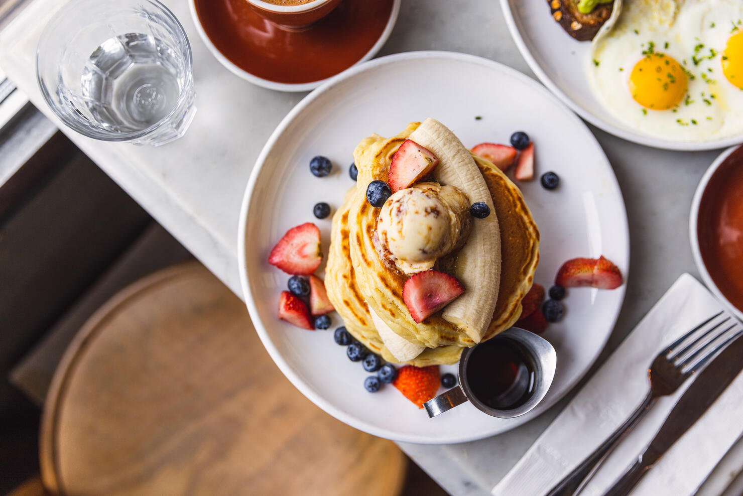 Pancakes with banana, strawberry and blueberry served in a cafe for breakfast, high angle view