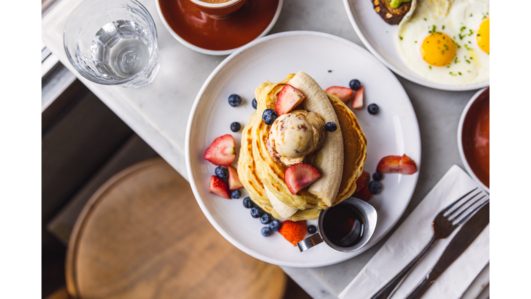 Pancakes with banana, strawberry and blueberry served in a cafe for breakfast, high angle view