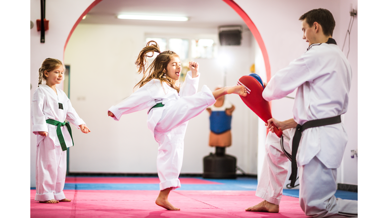 Two cute girls on taekwondo training, kicking and learning self-defence