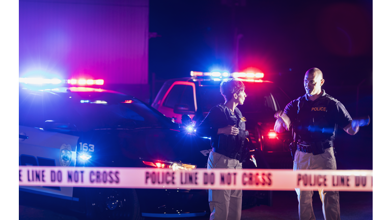 Two police officers standing in front of patrol cars