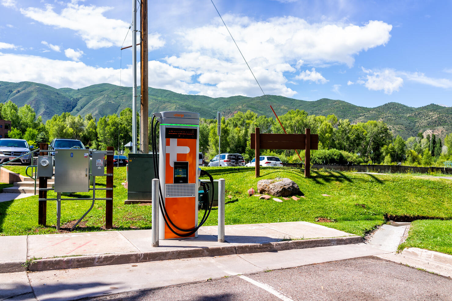 Electric vehicle charging station at parking lot space near farmers market with nobody during summer