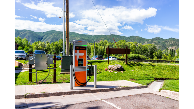 Electric vehicle charging station at parking lot space near farmers market with nobody during summer