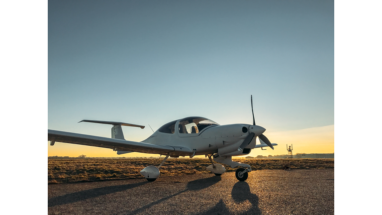 Parked small single engine propeller aircraft at sunset