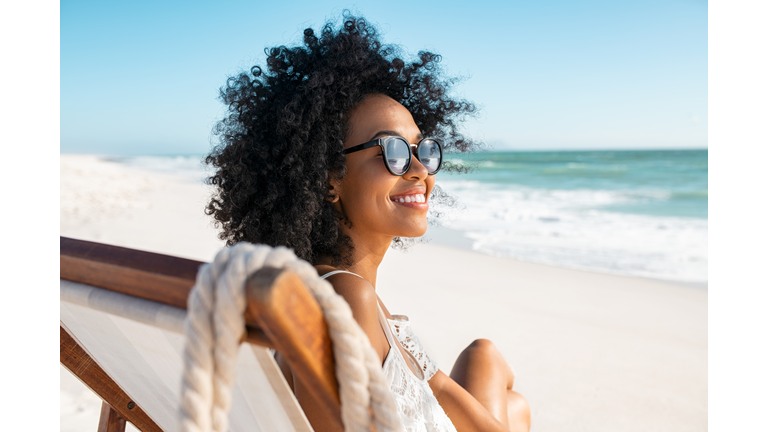 Carefree african woman relaxing on deck chair at tropical beach