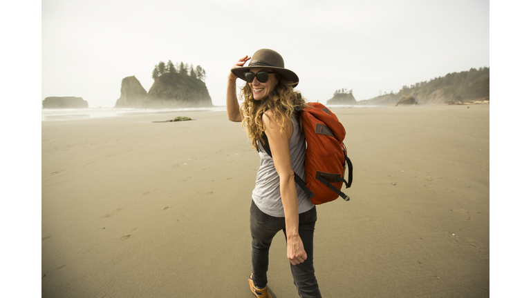A woman hiking along a remote beach.