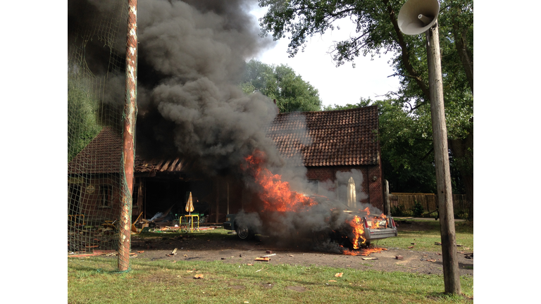 Car In Flames Against House