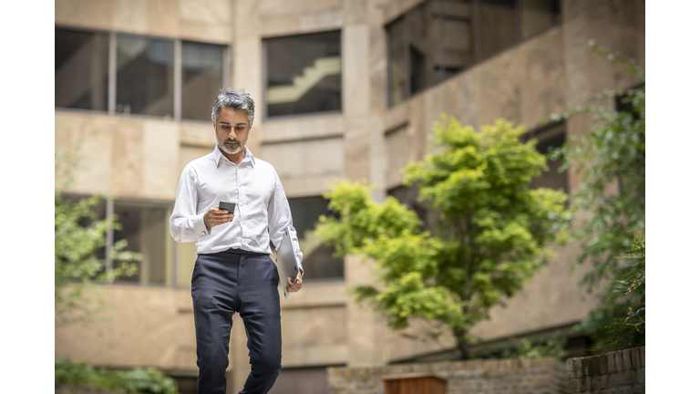 Mature businessman using smart phone in city