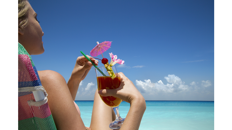Woman with tropical drink on beach