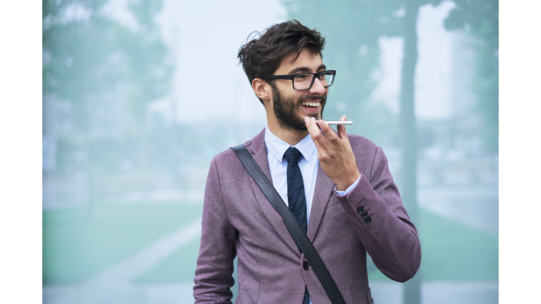 Portrait of happy young businessman on the phone outdoors