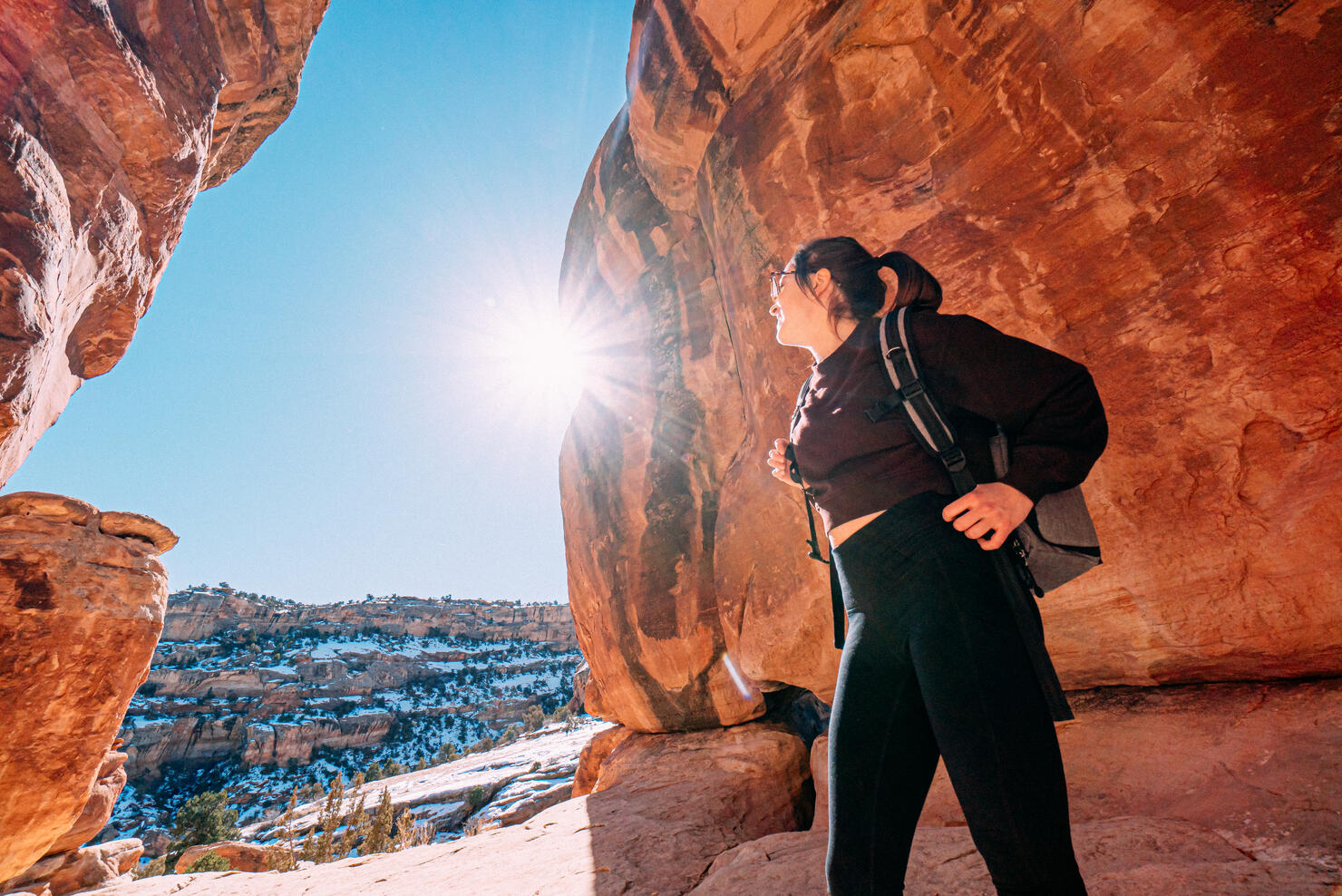 Wide Angle Portrait of a Cheerful Young Woman Standing, Holding Her Backpack Straps, and Enjoying the Views Outdoors While Visiting and Hiking at devil's Kitchen Trail Inside the Colorado National Monument