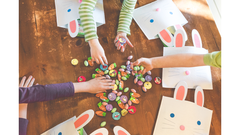 Cropped Image Of Children Holding Easter Candies On Wooden Floor